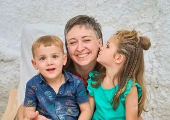 A parent hugging two children